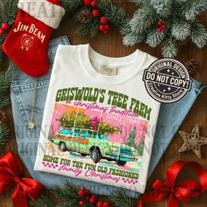 May include: White t-shirt with a graphic of a green station wagon carrying a Christmas tree, with text that reads "Griswold's Tree Farm, a Christmas tradition since 1989." The shirt is surrounded by Christmas decorations.