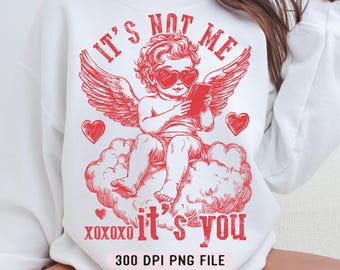 May include: Red graphic design on a white sweatshirt featuring a cupid with wings holding a phone and the text "It's not me it's you" with hearts and the text "XOXOXO" and "300 DPI PNG FILE".