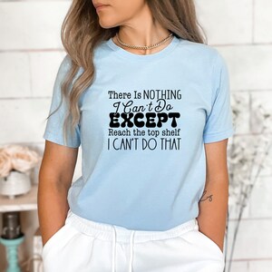 May include: A light blue t-shirt with a black graphic that reads "There is NOTHING I Can't Do EXCEPT Reach the top shelf I CAN'T DO THAT".