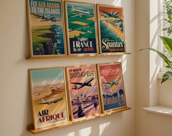 Puede incluir: Seis carteles de viaje vintage enmarcados con aviones, expuestos en estantes de madera. Los carteles muestran destinos como las Islas Aran, Francia y España, con colores vibrantes y tipografía retro. Los carteles están en marcos de madera.