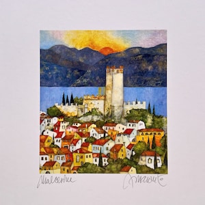 Può includere: Un dipinto ad acquerello di un piccolo paese incastonato in una valle con una grande torre al centro. Il paese è circondato da montagne e da un lago. Il cielo è di un arancione e giallo vibrante, che suggerisce un tramonto. Il dipinto è firmato "Marcelle" e "Amate"
