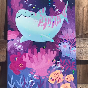 K&ouml;nnte beinhalten: Ein blauer und rosa Cartoon-Hai schwimmt in einer lila und rosa Unterwasser-Szene mit Korallen, Algen und Fischen. Der Hai hat einen freundlichen Ausdruck und ist von Blasen umgeben.