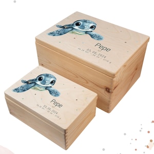 Könnte beinhalten: Zwei Holz-Andenkenboxen, eine große und eine kleine, mit hellem Holzfinish. Jede Box zeigt eine blaue Meeresschildkröten-Illustration auf dem Deckel, zusammen mit dem Namen "Pepe" und Geburtsdaten. Die Boxen sind mit Sternen verziert.