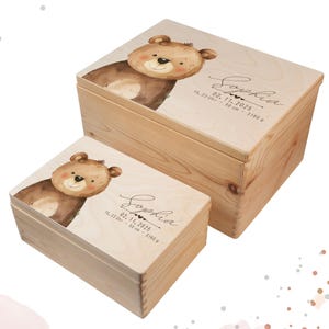 Könnte beinhalten: Zwei Holz-Andenkenboxen, eine große und eine kleine, mit hellem Holzfinish. Jeder Deckel der Box zeigt eine Aquarellillustration eines braunen Teddybären. Die Boxen sind mit dem Namen "Sophia" und Geburtsdaten personalisiert.