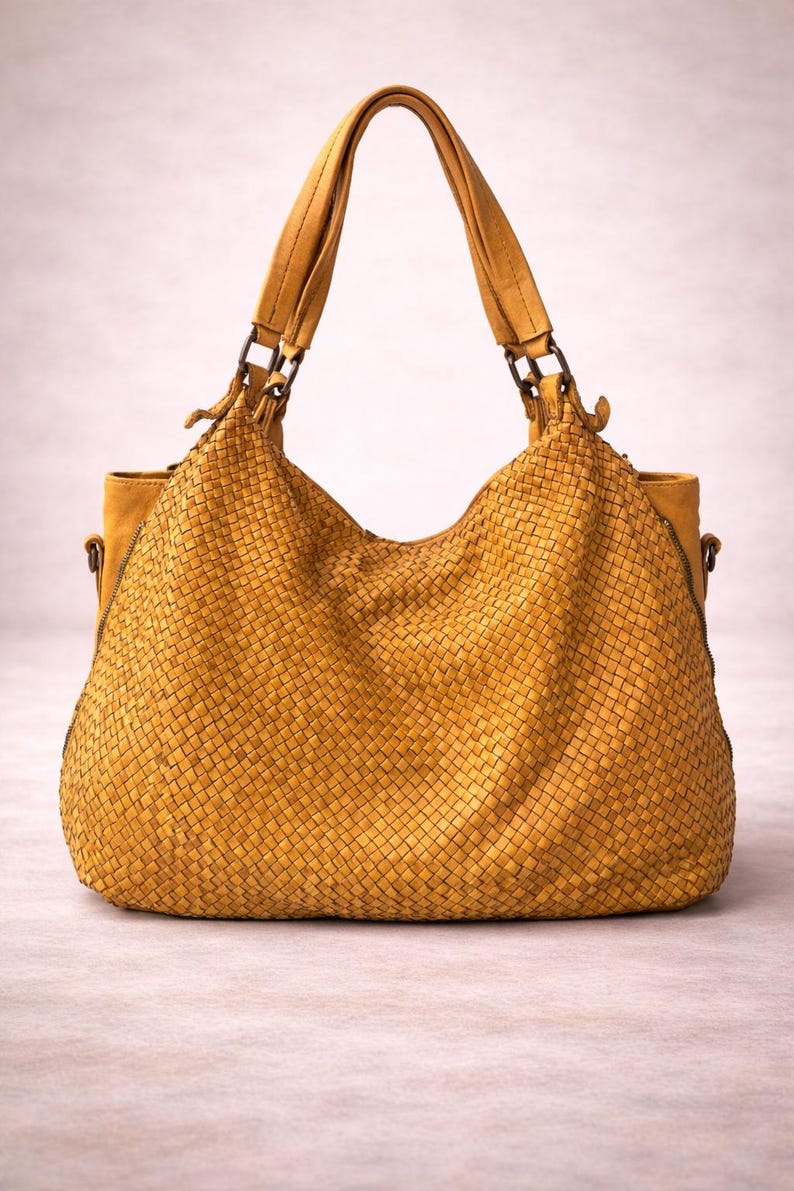 May include: Mustard yellow woven leather handbag with matching handles and a shoulder strap. The bag has a large, open design with a woven texture. The bag is a stylish accessory.