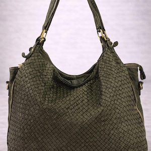 May include: Olive green woven leather handbag with two handles and gold-tone hardware. The bag has a large, rounded shape with a zipper closure and a woven texture throughout. The bag is designed for carrying items.