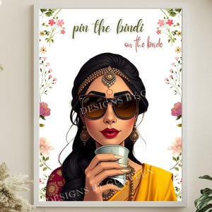 May include: Framed art print depicting a woman in sunglasses, Indian jewellery, and a yellow sari, holding a cup. The print has the text "pin the bindi on the bride" and is surrounded by floral accents.