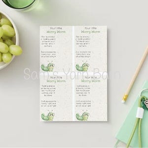 May include: A printed card with the text "Your little Worry Worm" and a poem about worries. The card features a cartoon worm illustration. A bowl of green grapes, a pencil, and a small notebook with keys are also in the image.