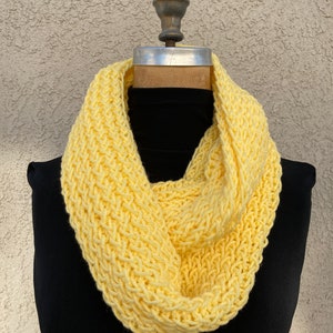 May include: A yellow knitted infinity scarf. The scarf is made of a soft, chunky yarn and is perfect for keeping warm in the winter.