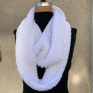 May include: A white knitted infinity scarf. The scarf is made of a soft, fluffy yarn and is perfect for keeping warm in the winter.
