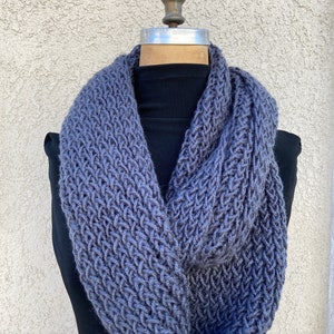 May include: A gray knitted infinity scarf with a textured stitch pattern.