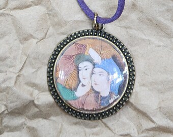May include: A round pendant necklace with a detailed antique bronze frame. The pendant features a miniature painting of two figures in traditional attire. The necklace has a purple suede cord.
