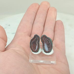 Op de afbeelding: Een set van drie keramische mokken met een gespikkelde, matte afwerking. De mokken zijn in crème, lichtgrijs en donkergrijs. Elke mok heeft een eenvoudig, minimalistisch ontwerp en een afgeronde handgreep.