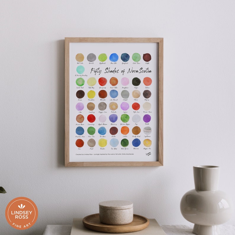 May include: A framed print of a watercolour painting titled "Fifty Shades of Nova Scotia". The print features 50 different shades of paint, each representing a different colour found in Nova Scotia. The print is surrounded by a light wood frame.