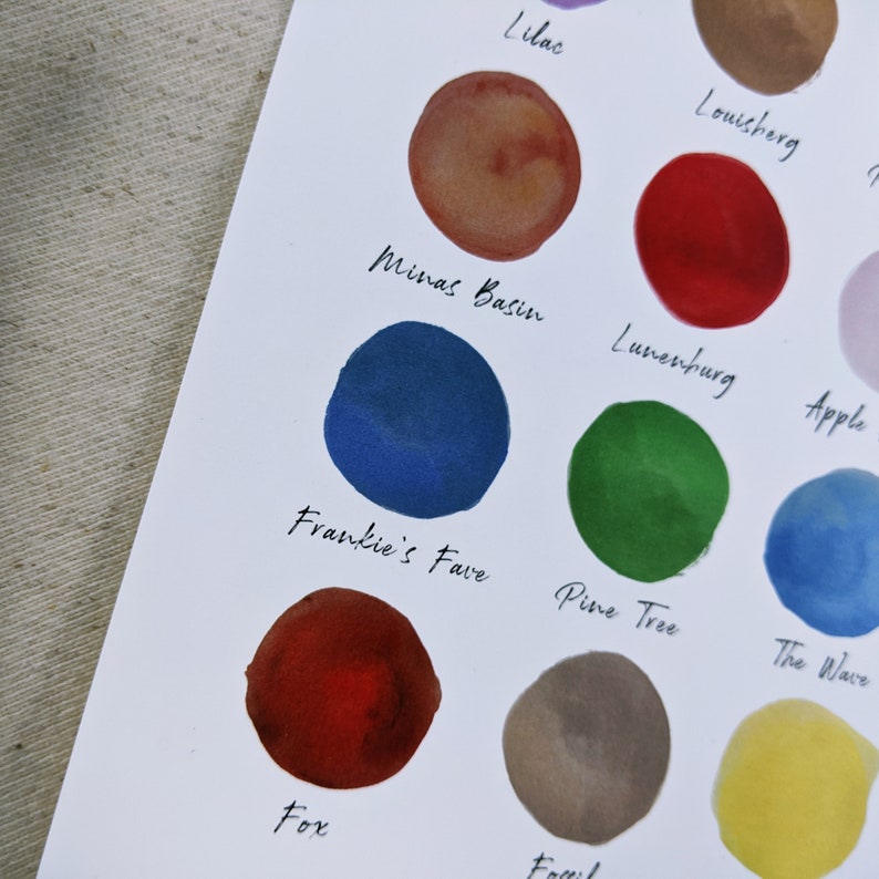 May include: A white sheet of paper with 10 different coloured ink swatches. Each swatch has a name written below it, including "Lilac", "Minas Basin", "Frankie's Fave", "Fox", "Pine Tree", "The Wave", "Lunerburg", "Apple", "Louisherg", and "Fossil".