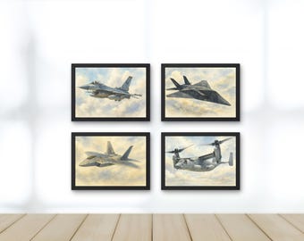 May include: Four framed art prints featuring watercolor paintings of military aircraft. The images include a fighter jet, a stealth bomber, another fighter jet, and a tiltrotor aircraft, all set against a cloudy sky.
