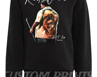 Könnte beinhalten: Schwarzer Kapuzenpullover mit einer Grafik einer Person mit Mikrofon und dem Text "Rod Wave" in weißer Schrift. Der Hoodie hat auch den Text "M. Lost LP" und "Rod Wave" in Weiß. Die Worte "Custom Prints" sind unten aufgedruckt.