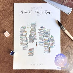 Op de afbeelding: Een aquarel-illustratie van een stad gemaakt van gestapelde boeken, met de tekst "Get lost in Powell's City of Books - Portland" bovenaan en onderaan de afbeelding.