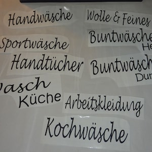 Könnte beinhalten: Neun weiße Etiketten mit schwarzem Text, jeweils mit einer anderen Wäschekategorie in Deutsch. Die Etiketten beinhalten "Handwäsche", "Sportwäsche", "Handtücher", "Wasch Küche", "Wolle & Feines", "Buntwäsche Hell", "Buntwäsche Dunkel", "Arbeitskleidung" und "Kochwäsche".