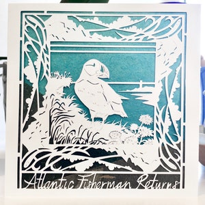 Tarjeta de felicitación artística con estampado de frailecillos 'Atlantic Fisherman Returns', cuadrada de 125 x 125, Puffin Coast, de Jessica Thomas