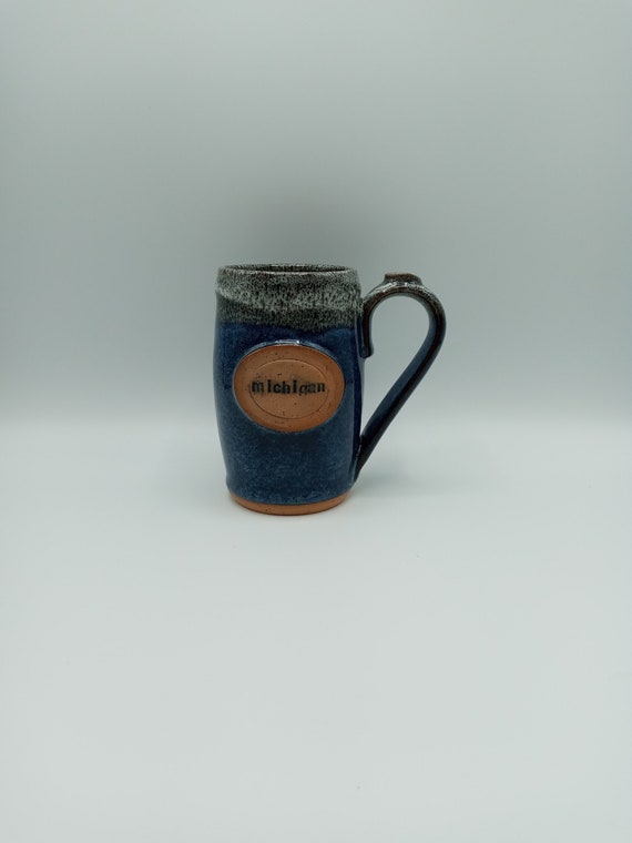 Blue glazed pottery mug with a Michigan badge