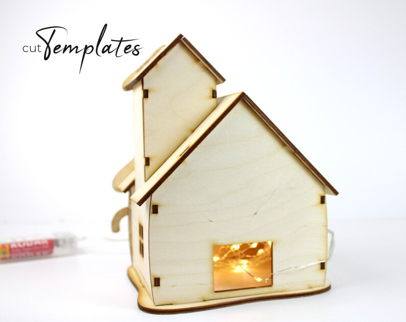 Puede incluir: Una casa de madera con un acabado marr&oacute;n claro y una ventana con luces de cadena en el interior. La casa es un proyecto de artesan&iacute;a de bricolaje y est&aacute; lista para ser ensamblada.