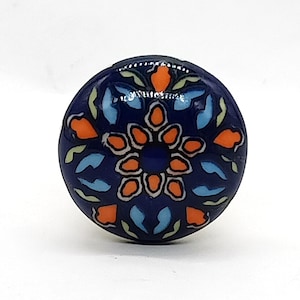 May include: A blue ceramic knob with a colorful floral design. The knob features a central orange flower with blue and white petals, surrounded by smaller orange flowers and green leaves.