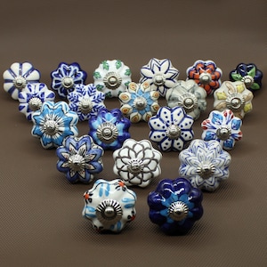 Op de afbeelding: Assortiment van 17 keramische ladeknopjes met bloemmotieven in tinten blauw, wit en bruin. Elke knop heeft een zilveren metalen basis.