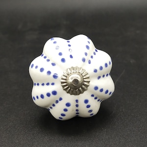 Könnte beinhalten: Weißer Keramik-Knopf für Schränke mit blauem Tupfenmuster und silberner Mitte.