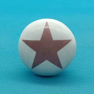 May include: White ceramic knob with a pink star design.