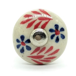 May include: White ceramic knob with red and blue floral design. The knob has a silver metal base.