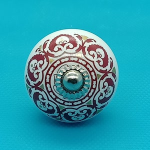 May include: White ceramic knob with a red and gold floral design. The knob has a silver metal centre.