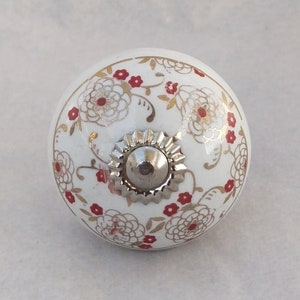 May include: White ceramic knob with a floral design in red and gold. The knob has a silver metal base.