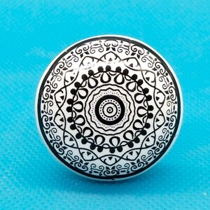May include: White ceramic knob with a black and white mandala design.