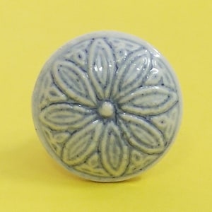 Peut inclure: Un bouton en céramique blanche avec un motif floral bleu. Le bouton a un motif en relief.