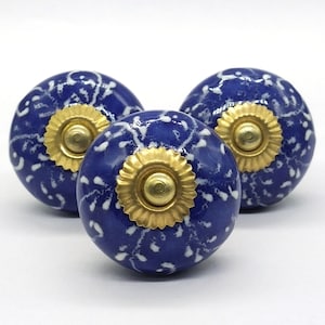 May include: Three blue ceramic knobs with white speckles and gold accents. The knobs are round and have a raised design.