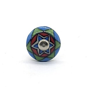 May include: A blue, green, and red ceramic knob with a white star in the center. The knob has a geometric pattern.