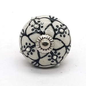 May include: White ceramic knob with a black floral design and a silver center.