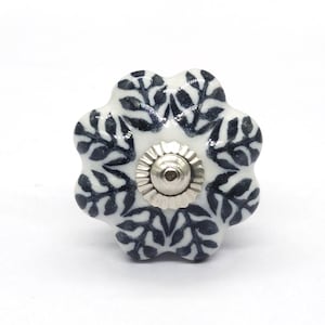 May include: White ceramic knob with a black floral design. The knob has a silver metal centre.