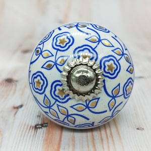 May include: White ceramic knob with a blue and gold floral pattern and a silver metal center.