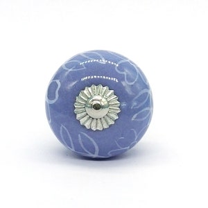 May include: A light blue ceramic knob with a white floral pattern. The knob has a silver metal base.