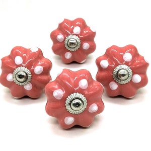 May include: Four coral pink ceramic cabinet knobs with white polka dots and silver accents.