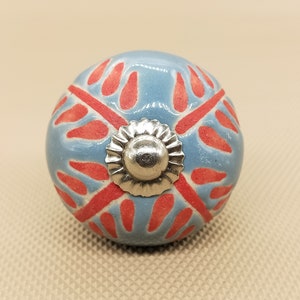 May include: A blue ceramic knob with a red and white floral design and a silver metal center.
