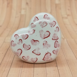May include: White ceramic heart-shaped knob with a red and pink heart pattern.