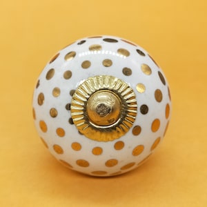 May include: White ceramic knob with gold polka dots and a gold center ring.