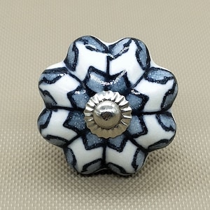 May include: A white ceramic knob with a gray and white geometric pattern. The knob has a silver metal base.