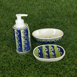 May include: A bathroom set with a blue and green floral design. The set includes a soap dispenser, a soap dish, and a dish for holding a bar of soap.