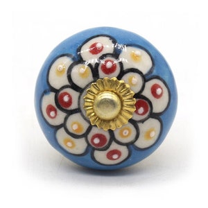 May include: A blue ceramic knob with a white and red floral design and a gold center.