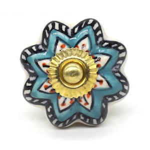 Puede incluir: Un pomo de armario de cerámica azul y blanco con un centro dorado y un diseño floral.