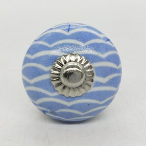 May include: A blue and white ceramic knob with a silver metal center. The knob has a wavy pattern.